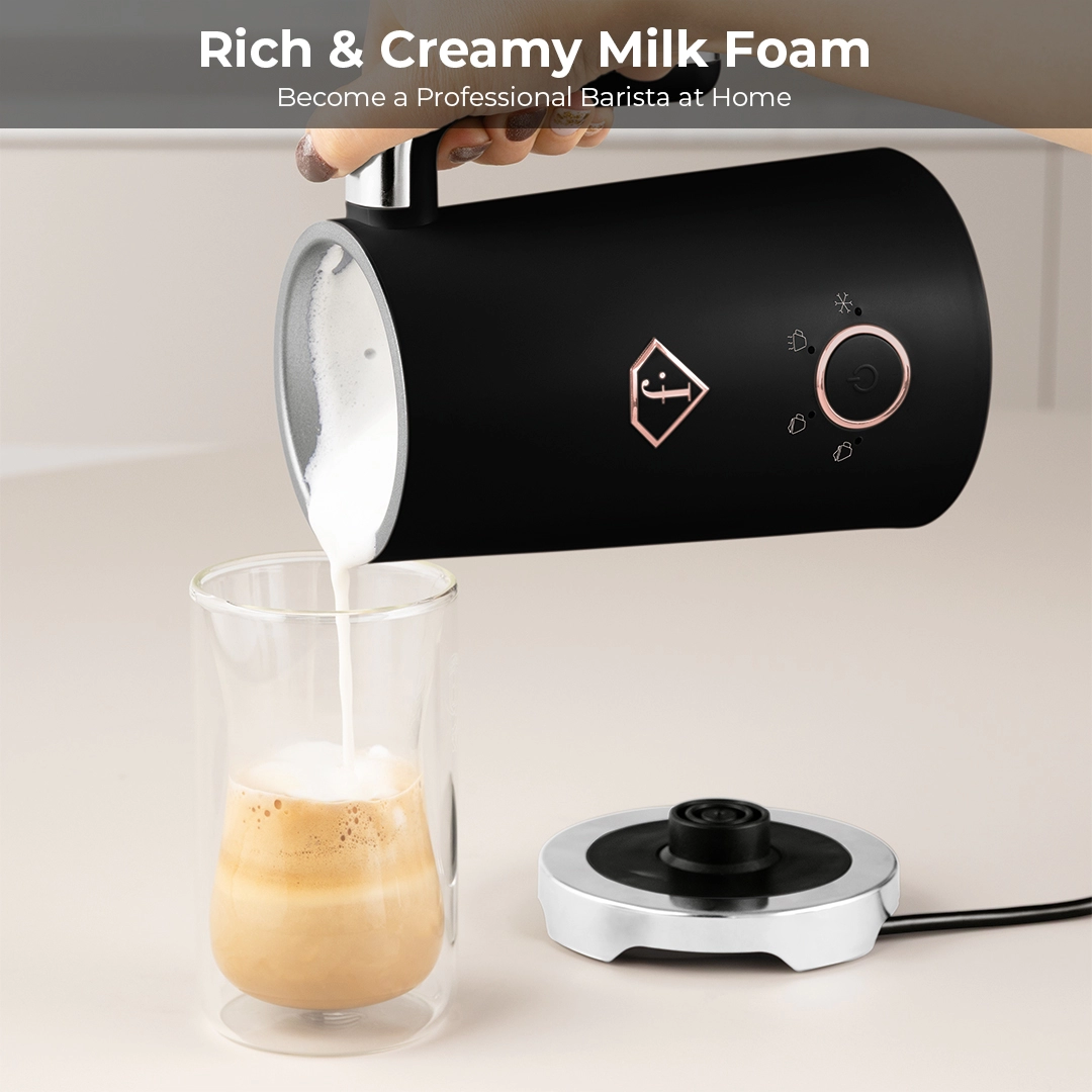 Milk foam pouring from the jug into a tall latte glass