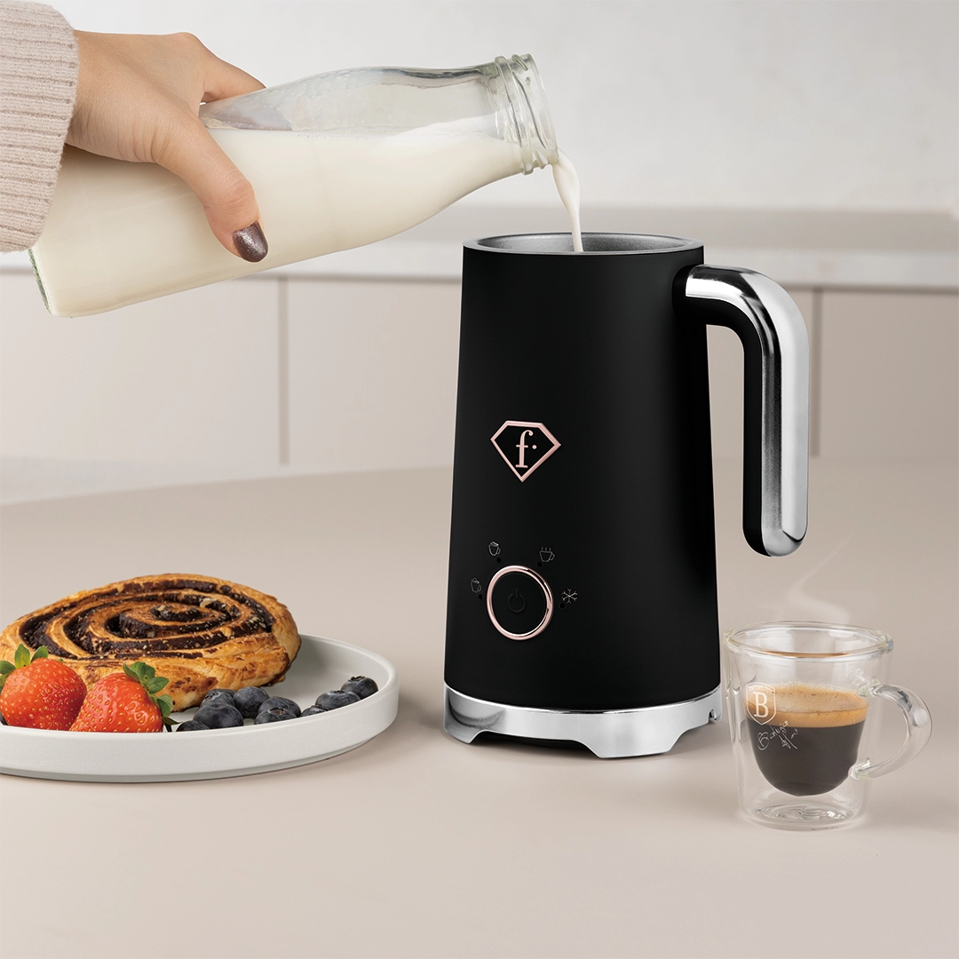 Pouring milk into the jug at a breakfast table beside pastry and an espresso